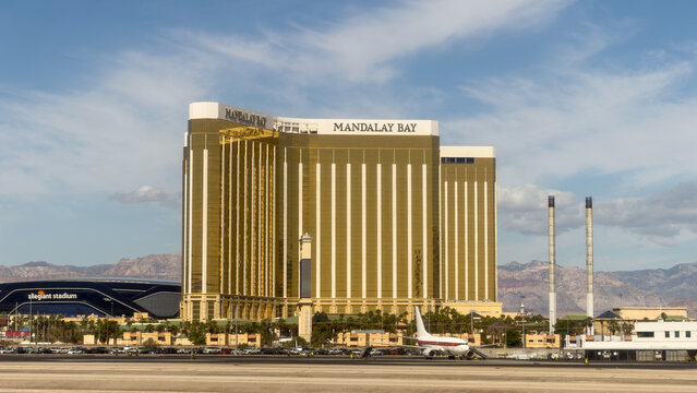 LAS VEGAS, NV, APR 28, 2026: Mandalay Bay's golden hotel tower in Las Vegas, seen from the airport tarmac with Allegiant Stadium and a parked airplane in the foreground