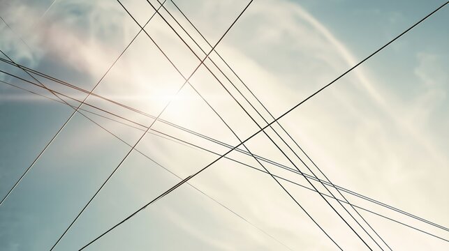 Utility wires forming geometric lines and abstract shapes in a minimalist view, sun shining through clouds