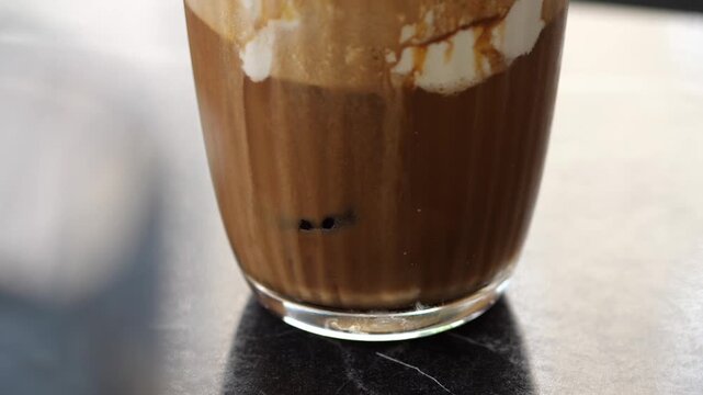 Close-Up of Iced Coffee Drink with Cream Foam | Delicious Cold Brew Iced Latte in Glass with Ice Cubes