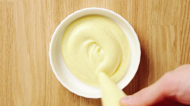 Prepared custard is piped from pastry bag into ramekin. Pastry school lesson teaches steady pressure and portion control. Students practise clean filling for dessert cups, tartlets or plated sweets.
