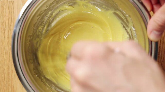 Pale yolk and sugar mixture is stirred slowly with whisk. Lesson shows correct colour and thickness after beating. Students check ribbon stage for custard, tiramisu, ice cream or pastry cream.