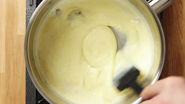 Thickening mixture is stirred with silicone spatula in saucepan. Warm dairy turns into smooth homemade vanilla pudding. Serve chilled dessert with berries, caramel, chocolate, nuts or whipped cream.