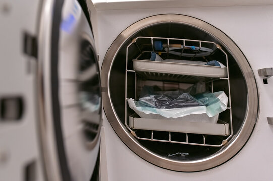 Dental sterilization equipment with trays and wrapped instruments inside autoclave machine
