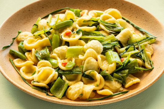 A plate of orecchiette pasta with cooked, sliced puntarelle stalks, pepperoncino and olive oil (Orecchiette con cime di cicoria).