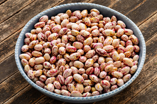 Fresh-shelled borlotti beans (fagioli sgranati) on rustic wood, a key ingredient in Tuscan beans with oil and rosemary or sage (Fagioli all'uccelletto, Fagioli all'olio).