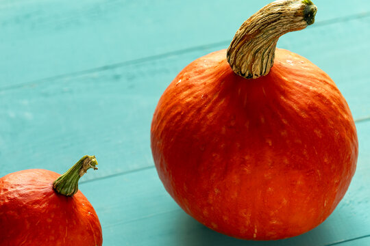 Small and large Hokkaido pumpkins on blue-painted wooden boards.