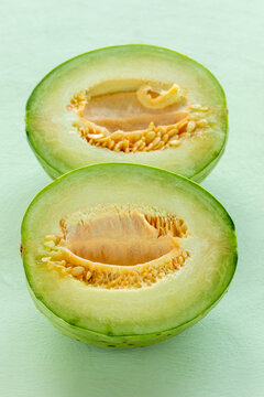Two halves of unripe Charentais melon -  the best substitute for green papaya in Thai Som Tam salad. Pastel green background.