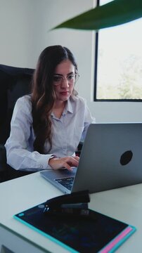 Focused young businesswoman working on laptop computer at her office desk