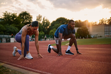 Fototapeta premium Athletes starting a race on running track at sunset