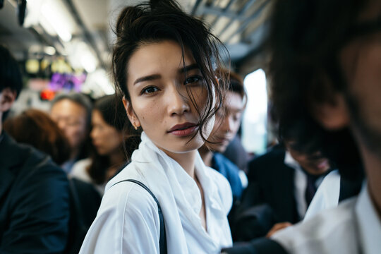 Young Asian Businesswoman Commuting on Crowded Subway Train