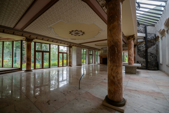 Abandoned luxury mansion interior with marble hall, ornate fireplace, swimming pool and glass facade