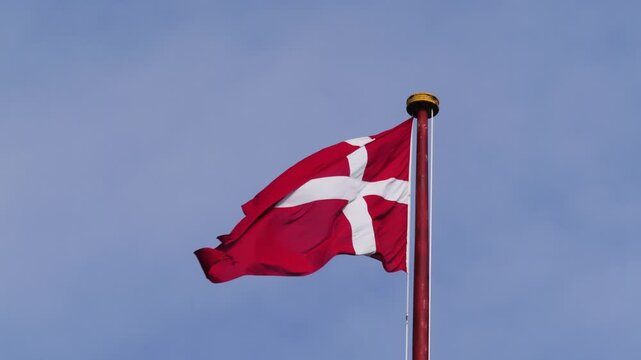 Danish flag (Dannebrog) waving on flagpole against blue sky