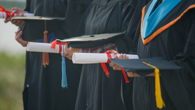 Graduates Holding Diplomas and Academic Caps During Graduation Ceremony