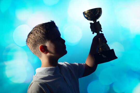 Boy Celebrating with Golden Trophy  cup  and Confetti on Blue Background