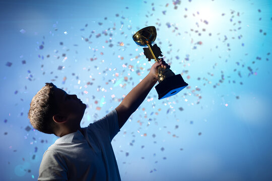 Silhouette of Boy Raising Trophy Amid Falling Confetti