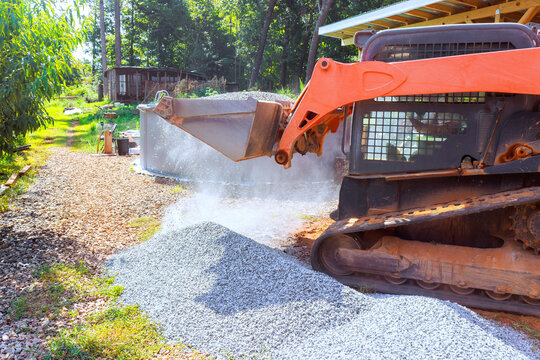 Bulldozer spreads gravel on construction site in wooded area