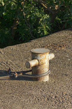 old rusty iron bollard with a steel anchor rope in the dock