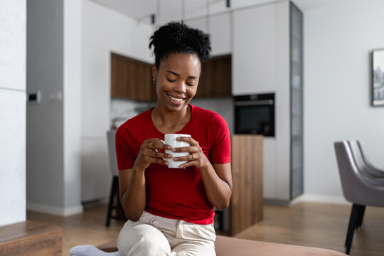 Smiling woman enjoying coffee at home in a modern kitchen during a relaxed morning