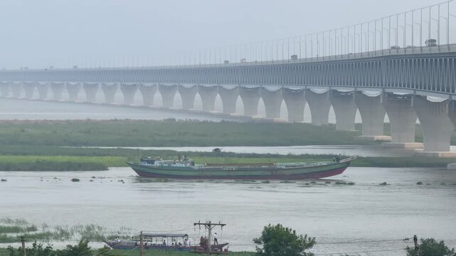 Cargo Vessel Sailing Beneath Padma Multipurpose Bridge with Highway Traffic in Bangladesh