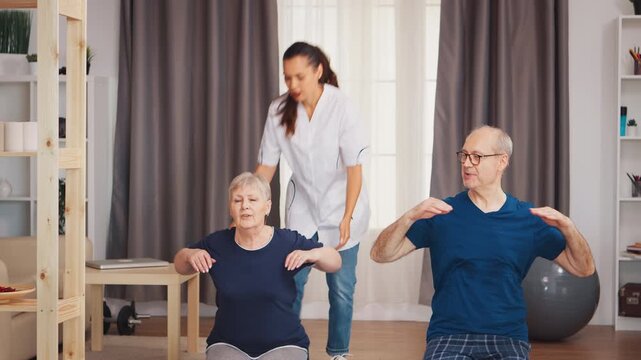 Physiotherapist guiding senior couple through home mobility exercises