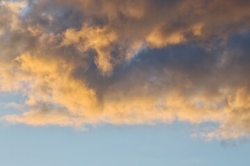 Obraz premium Golden sunset sunlight on dark storm clouds above clear blue sky background