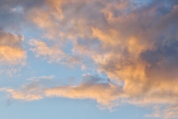 Obraz premium Scattered golden peach clouds on blue twilight sky background for sky replacement
