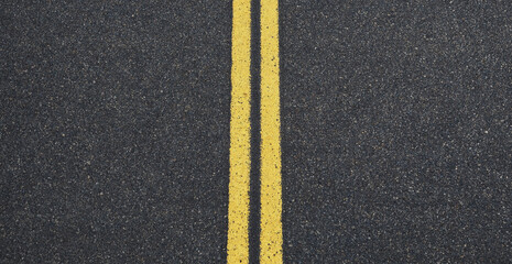Top down view of asphalt road surface with double yellow center lines for traffic lane separation © Nurjahan _Studio