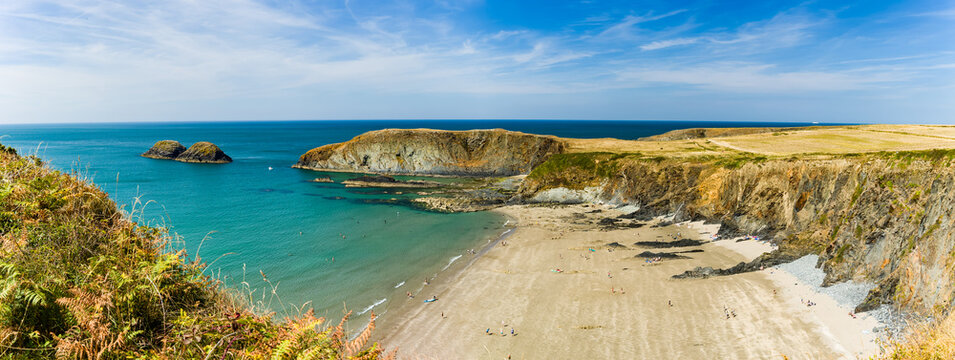 Sandy beach and rocky cliffs at Traeth Llyfn, Pembrokeshire, turquoise water washing onto the shoreline below rugged coastal headlands in summer