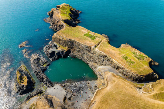 Blue Lagoon near Abereiddy in Pembrokeshire, Wales, flooded slate quarry surrounded by rocky cliffs and coastal path, high angle drone view