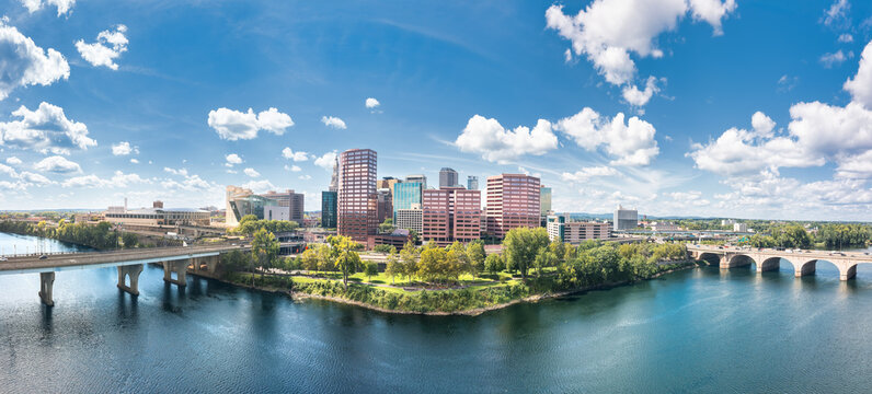 Hartford skyline panorama from across the Connecticut River, framed by Founders bridge and Bulkeley bridges, showcasing downtown buildings, the waterfront, and the capital of Connecticut.