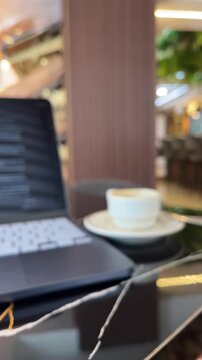 Laptop and coffee cup on table in luxury cafe blurred background