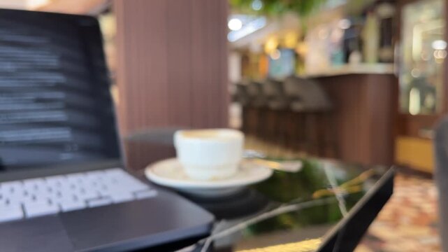 Laptop and coffee cup on cafe table with panning copy space