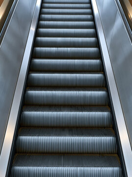 Escalator metal stair vertical architectural interior modern silver symmetry perspective minimal industrial pattern texture structure transportation moving steps rail hallway building mall airport