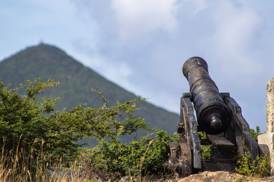 Old iron cannon at a historic fort above a green hill on Sint Maarten