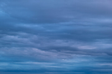 Obraz premium Dark overcast sky with dense gray clouds. Moody weather conditions block the sunlight. Thick atmospheric layers foretell upcoming rain.