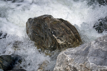Boulder in rushing white water of a mountain stream close up © Matt