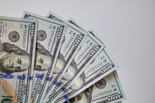 Creative vertical composition of american currency bills arranged as an open fan on a clean white surface. Elegant visual layout representing financial progress, incremental income growth, accounting
