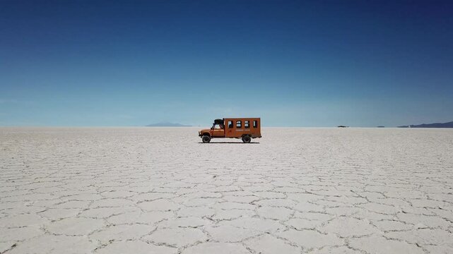 Scenic drone reveal of a Yellow camper truck parked at Salar de Uyuni - Uyuni Salt flats desert