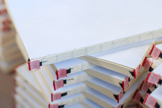 Stacks of unfinished book blocks in a printing house. Industrial bookbinding production process showing unfinished components in a manufacturing facility. Selective focus.