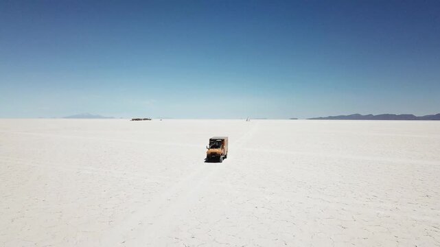 Ultra-wide scenic drone view of a Yellow camper truck driving across Salar de Uyuni - Uyuni Salt flats desert