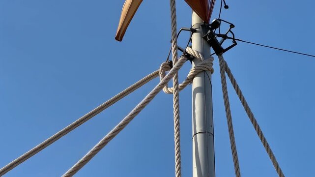 Flagpole rope swaying against a mast