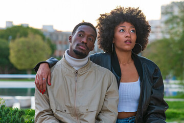 Fototapeta premium Thoughtful young Black couple sitting together in an urban park