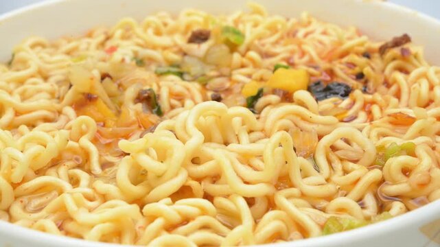 closeup stewed beef instant noodles in a white bowl with vegetable and meat toppings in rich soup rotating
