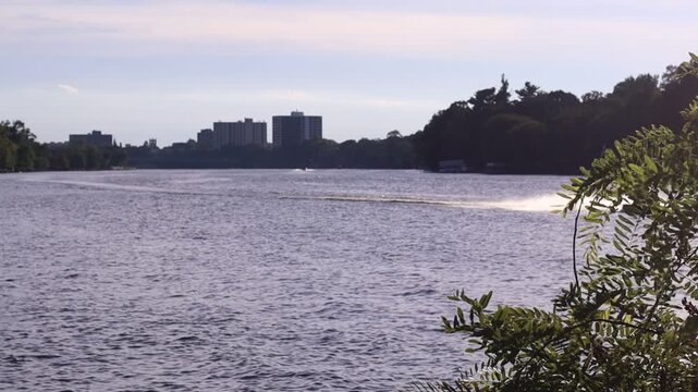 A jet ski driving up the river water with the city skyline behind it in Rockford, Illinois.