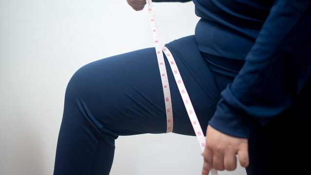 Plus-Size Woman Measuring Her Body with a Measuring Tape While Wearing Weight-Loss Shapewear