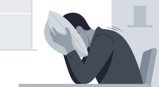 Man Hiding Face In Pillow Feeling Overwhelmed And Stressed Out At Desk