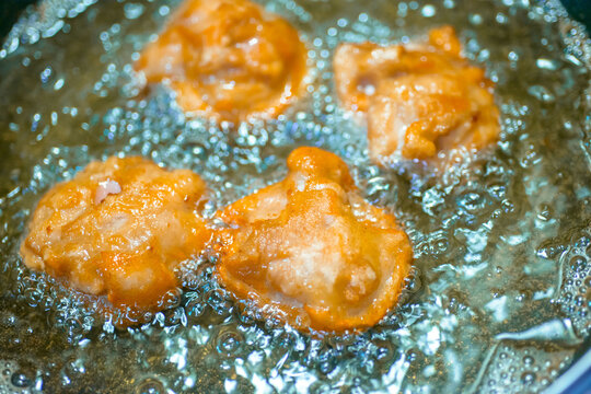 Golden fried chicken karaage being cooked in hot oil in a wok, cooking in progress