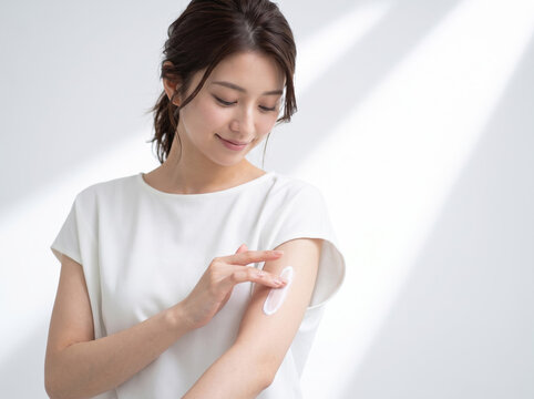 腕にボディークリームを塗ってスキンケアをする女性