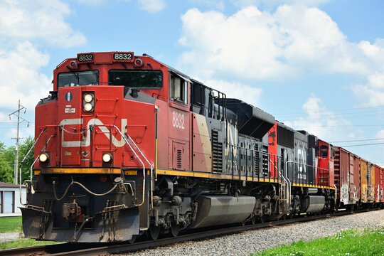 Multiple locomotives lead a Canadian National Railway merchandse freight train southbound through a small north central Illinois community.