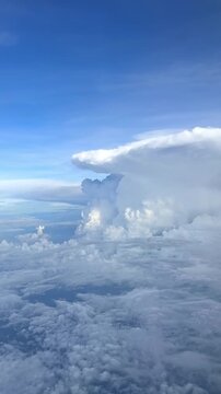 Large cumulonimbus cloud formation with a flat top and blue sky visible from above, showcasing a dramatic weather phenomenon in the atmosphere. Slow motion vertical footage, 4K, copyspace